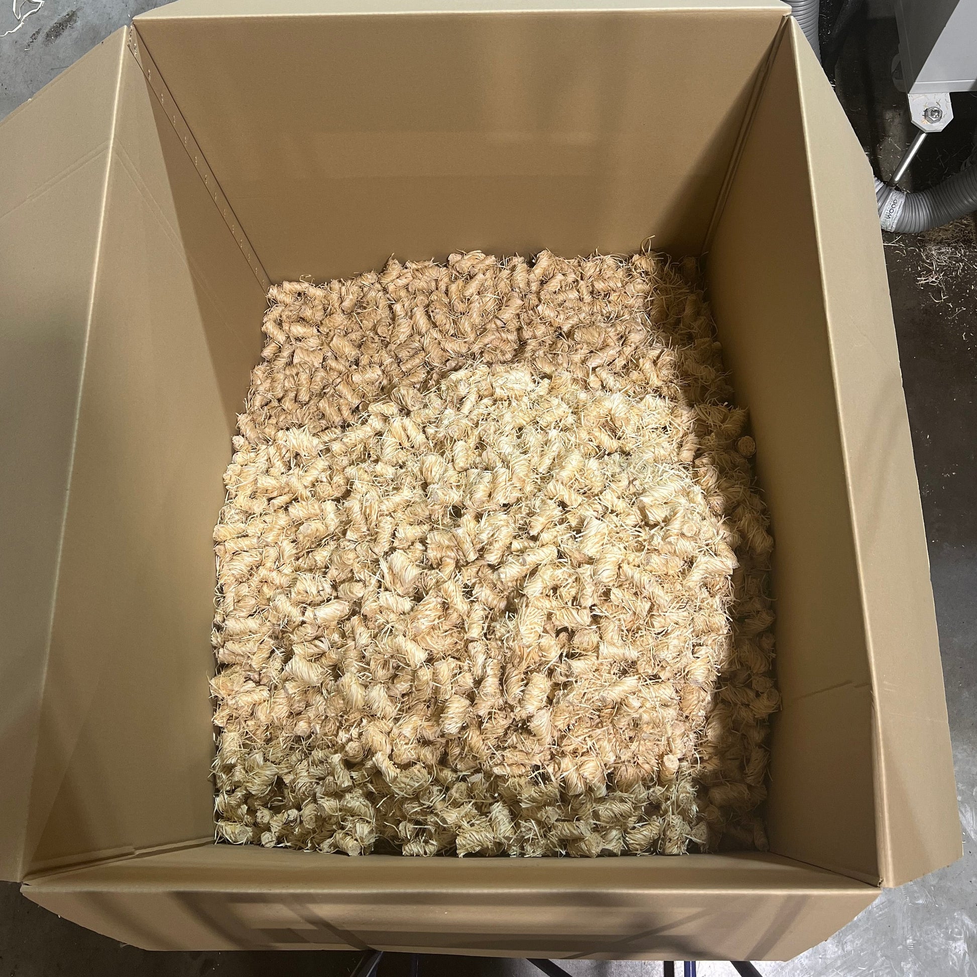 Overhead view of an open pallet box filled with loose Flamers natural firelighters ready for repackaging